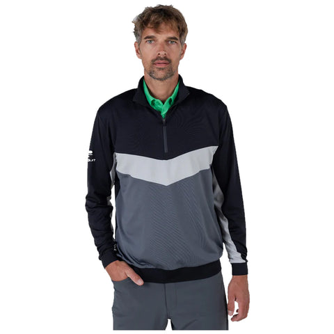 A man stands confidently wearing a black and gray athletic jacket with a quarter-zip and green shirt underneath in a neutral background showcasing his outfit for potential outdoor activities.