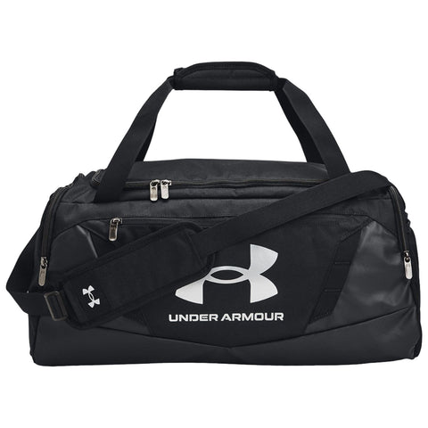 A black duffel bag with dual handles and a removable shoulder strap sits on a flat surface displaying a large white Under Armour logo and brand name on its side.