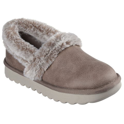 A cozy slipper with a soft faux fur cuff rests on a flat surface featuring a textured base and a round toe in a neutral brown shade emphasizing comfort in a home setting