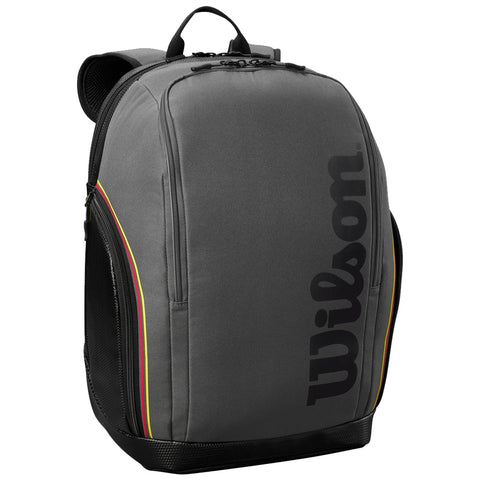 A gray backpack is standing upright showcasing a large black logo on its side with colorful stripes along the edge and zippered compartments visible on the front and sides.