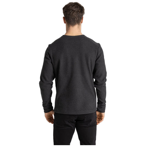 A person wearing a black long-sleeve shirt stands with their back facing the viewer in a neutral setting against a white background, suggesting a casual or relaxed atmosphere.