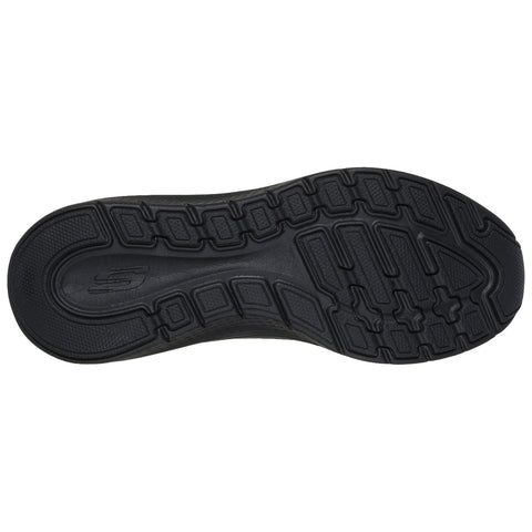 A black athletic shoe sole is displayed flat with a patterned tread designed for traction and grip resting against a neutral background highlighting its contours and texture.