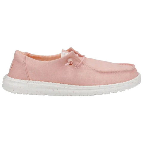 A light pink shoe with a textured surface rests on a white speckled sole featuring a lace-up design and a small logo on the heel in an undefined setting.