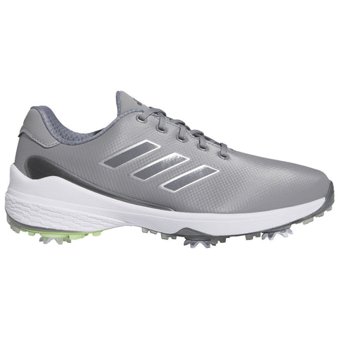 A gray sports shoe is displayed positioned upright with laces tied showcasing a smooth surface and three diagonal stripes on the side the sole features prominent spikes for traction on grass