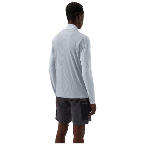 A person wearing a light long-sleeve shirt and dark shorts stands facing away in a neutral background. The outfit appears suitable for casual outdoor or athletic activities.