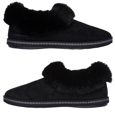 Black slippers with a soft, fluffy cuff are displayed side by side showcasing a sleek design made of suede and lined with faux fur for comfort in a home setting.