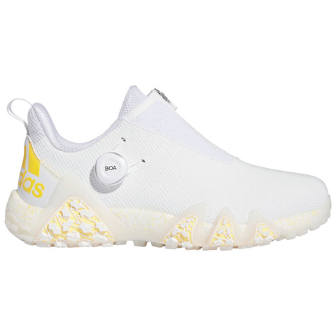 A white sneaker features a slip-on design with a textured upper and a yellow logo on the side. It includes a BOA lacing system for adjustable fit and a distinctive sole pattern.