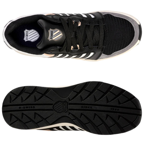 Black and gray athletic shoe with white stripes lies flat showing the top and sole featuring a textured surface and logo near the heel in a neutral background.