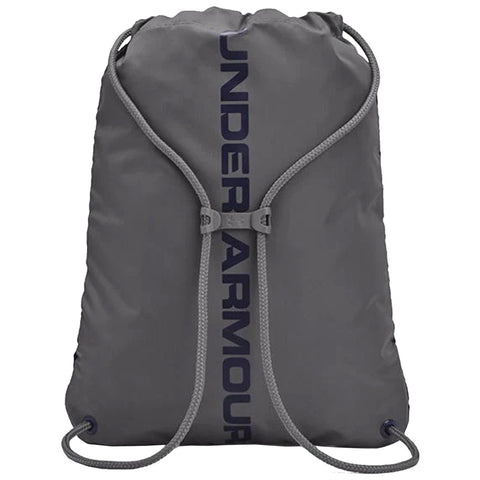 A gray drawstring backpack with the brand name Under Armour prominently displayed vertically on the front is shown resting on a flat surface with a simple fabric texture.