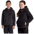 Two children stand side by side wearing dark fuzzy zip-up jackets with hoods and bright zippers. They are smiling in a neutral background suggesting a casual or outdoor context.