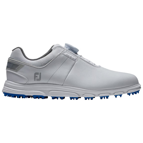 A white golf shoe made of synthetic material is displayed side-on featuring a spikeless blue rubber sole and a dial system for adjustment in a clean studio background.