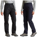 Two pairs of outdoor pants are displayed side by side one in black featuring a cargo pocket and the other in navy both are worn by a person in hiking boots.