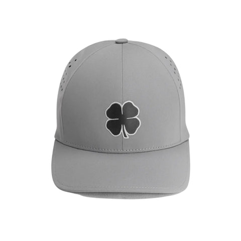 A gray baseball cap sits upright showcasing a black four-leaf clover emblem on the front with small ventilation holes on the sides against a neutral background.