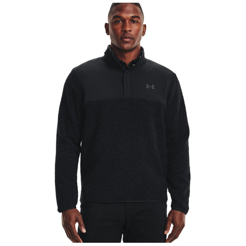 A man is wearing a black fleece pullover with a quarter-zip design featuring a smooth upper section and textured lower half in a neutral backdrop, projecting a casual athletic style.