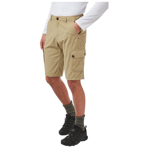 Beige cargo shorts are worn by a person who stands with one hand in a pocket and the other at their side in a neutral setting. They are paired with dark footwear and green socks.