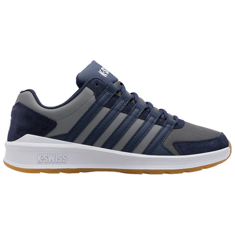 A navy and gray athletic shoe sits on a white background showcasing a mesh and suede design with prominent laces and the brand logo visible on the tongue and side