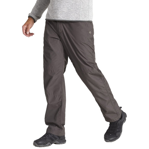 A person is walking in outdoor pants and black shoes with a grey long-sleeve top in a neutral setting likely outdoors or in casual environment.