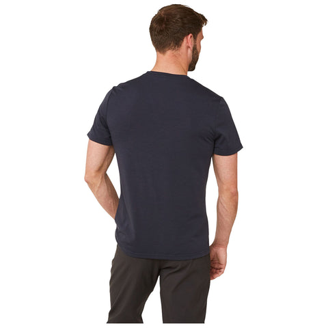 A man wearing a navy blue t-shirt stands with his back towards the viewer in a neutral background, showing casual attire and relaxed posture.