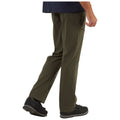 A person in olive-green pants walks forward while wearing black shoes in a plain, unobtrusive environment. The pants feature a zippered pocket on the side for utility.