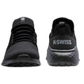 Black athletic shoes are positioned upright displaying a mesh upper and rubber sole showcasing K-Swiss branding on the rear in a simple and modern design against a neutral background.