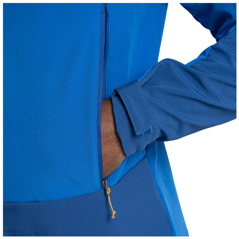 A blue garment is draped loosely over a person's torso with a hand placed in a pocket while the other arm is relaxed at the side showcasing a zipper detail.