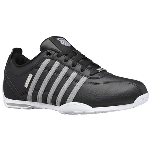 Black athletic shoe featuring gray stripes on the side is positioned against a neutral background highlighting its design and texture emphasizing its sporty and stylish appearance.