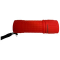 A red flashlight is resting horizontally with a textured grip surface and a lanyard attached, designed for illumination in dark areas or during outdoor activities.