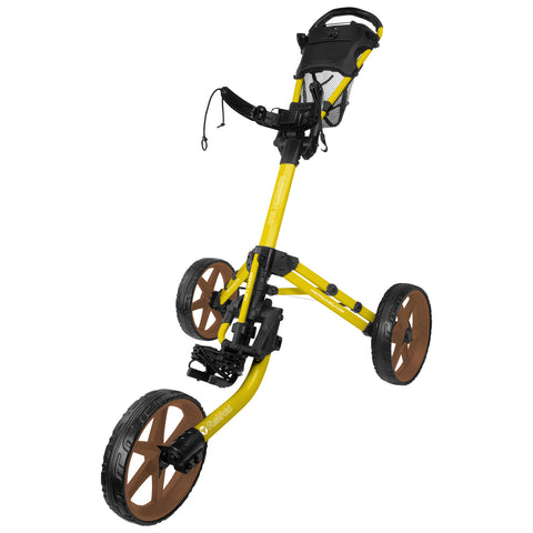 A yellow golf push cart stands upright with three wheels the front wheels are brown the handle features a mesh pocket and a strap for securing belongings in use on a golf course.