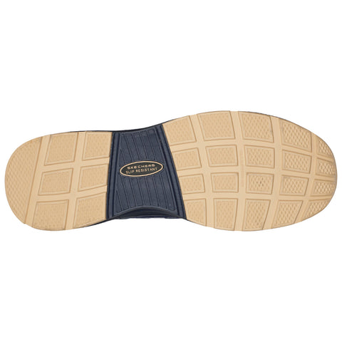 A shoe sole with patterned grooves is positioned on a flat surface showcasing a brown rubber material with a black insert featuring the words SKETCHERS SLIP RESISTANT