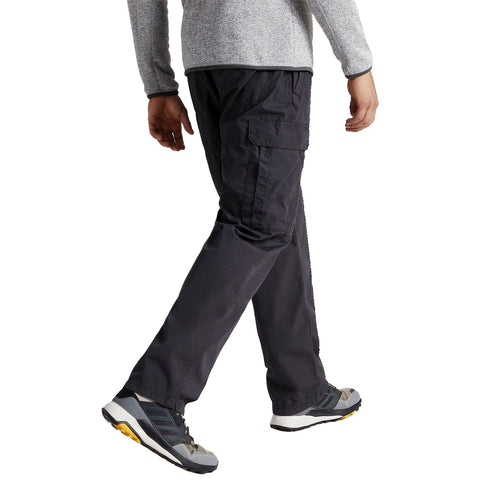 A person is walking with a casual stride wearing dark cargo pants and grey athletic shoes in a neutral background suggesting an indoor or outdoor setting.