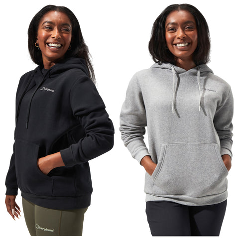 A smiling woman stands confidently wearing two different hoodies one black and one gray both with front pockets showcasing a casual style in a bright background