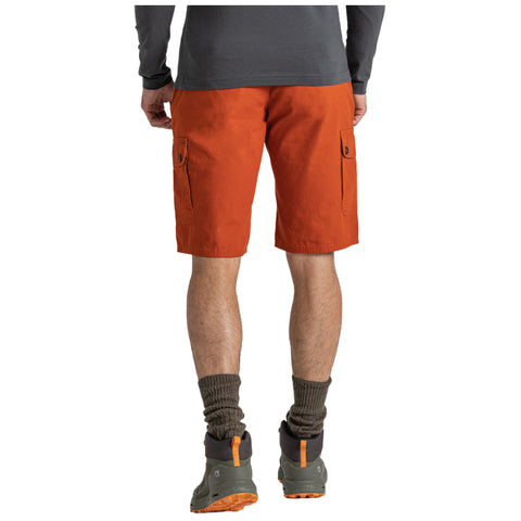 A person stands with their back visible, wearing orange cargo shorts, green hiking boots, and dark socks, in a neutral setting that emphasizes their outfit without specific background details.