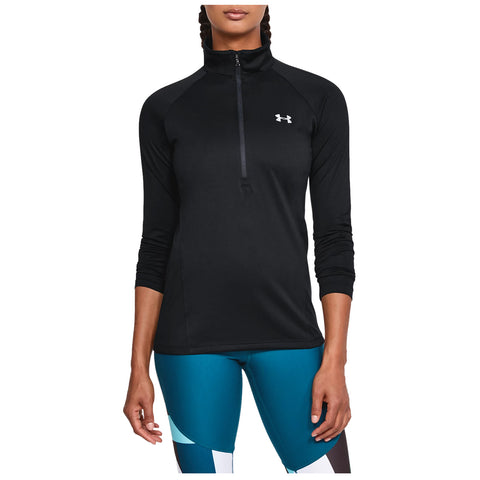 A person is wearing a black athletic top with a half-zip and long sleeves paired with colorful leggings while standing in a neutral setting with a focus on fitness apparel.