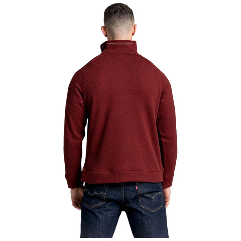 A person is standing with their back facing the viewer wearing a burgundy pullover and dark jeans in a neutral background, suggesting a casual outdoor or indoor setting.