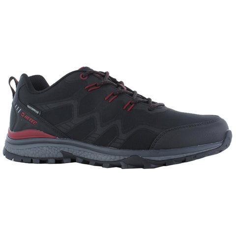 A black hiking shoe with red accents sits on a flat surface displaying a rugged outsole designed for traction featuring a waterproof upper for outdoor activities.