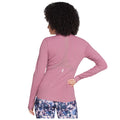 A person wearing a pink long-sleeved athletic top faces away while adjusting their clothing. They are in a neutral background suggesting a focus on activewear or fitness.