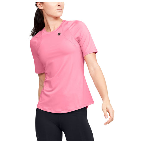 A person wearing a pink athletic shirt is striking a pose with a confident expression while standing in a neutral space, suggesting a focus on fitness or active lifestyle.