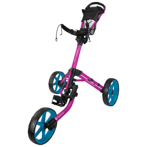 A golf push cart with a pink frame and blue wheels is positioned upright. It features a handle and a mesh holder, designed for transporting golf clubs across the course.