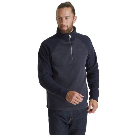 A man wearing a dark pullover fleece with a zip stands confidently with one hand raised slightly in a casual pose against a plain white background