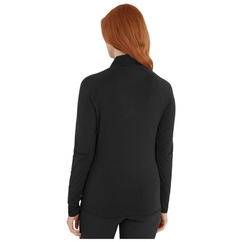 A person with long red hair is wearing a black long-sleeve top, viewed from the back, standing in an undefined space with a plain background.