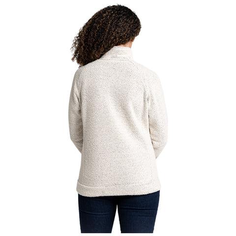 A person with curly hair is wearing a light-colored pullover sweater seen from behind standing still in a neutral space emphasizing comfort and casual style