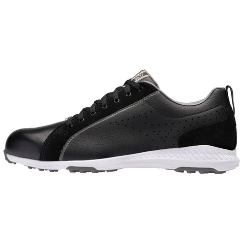 A black shoe with synthetic leather and suede detailing is displayed sideways features a white sole and perforated design elements for breathability in a neutral background.