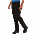 Craghoppers Mens Kiwi Pro II Walking Trousers A person is walking in black pants and black shoes with blue accents while wearing a blue shirt in a neutral environment likely indoors or on a smooth surface.