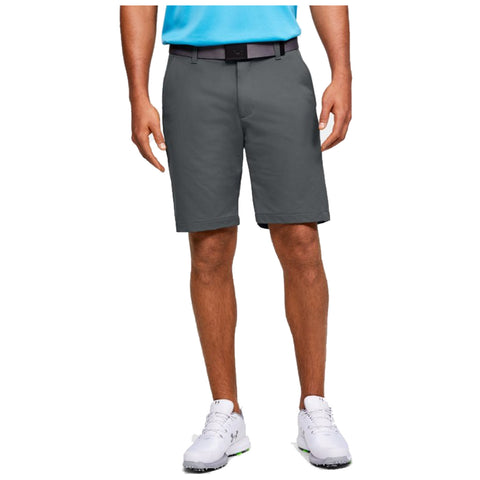 A pair of grey golf shorts is worn by a man who stands with one hand raised in a casual pose while dressed in a blue shirt and white golf shoes