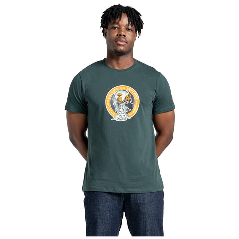 A young man is standing with his arms relaxed at his sides wearing a dark green t-shirt featuring a circular graphic with the text Outdoor Calling Go Explore and a design of mountains and a flame