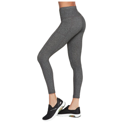 High-waisted, form-fitting gray leggings cover the legs of a person who is standing. They wear black athletic shoes. The setting appears to be minimalistic and clean, focusing on the apparel.