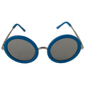 Round sunglasses with a bright blue frame and dark lenses are positioned upright against a neutral background showcasing their distinctive style and color.