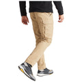 A person is walking, wearing beige cargo pants and gray athletic shoes, with one arm slightly raised, in a neutral setting likely to be outdoors or casual.