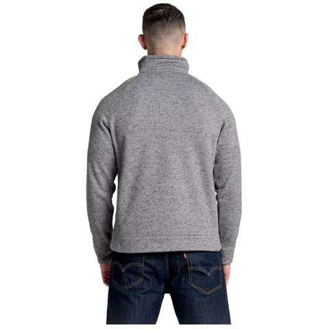 A person is standing with their back to the viewer wearing a gray pullover sweater and dark jeans in a neutral setting with no distinct features or context visible.