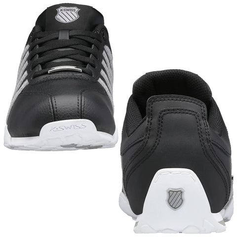 Black athletic shoes with a leather upper and white sole are displayed angled to show both the front and back. The design includes brand logos and a gray stripe pattern.